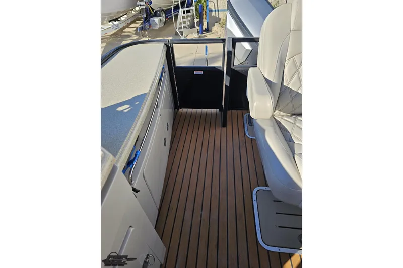Slide: The Image of 2015 Bennington 2550 QBR boat interior with wood flooring and cushioned seating. - 99