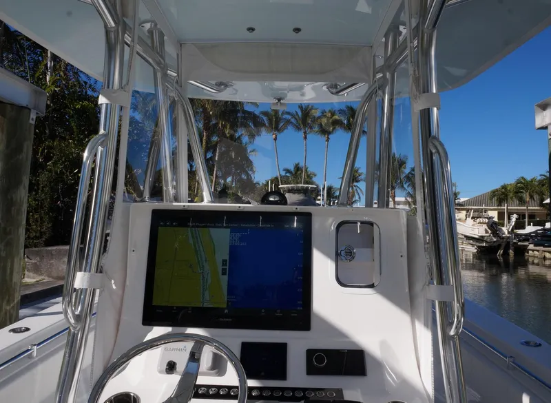 Slide: The Image of 2023 Contender 32 ST boat dashboard with navigation screen, steering wheel, and marina view. - 7