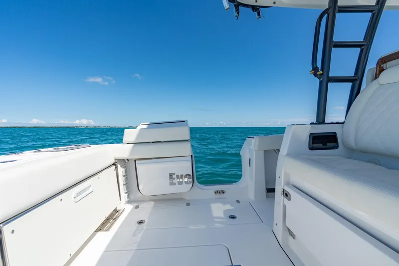 Slide: The Image of 2025 Everglades 375 Center Console boat interior with ocean view, featuring white seating and clear skies. - 19