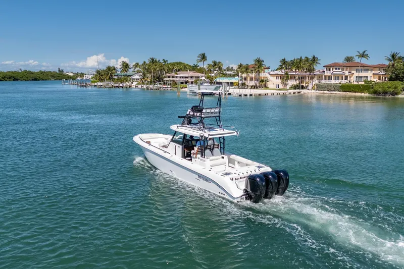 Slide: The Image of 2025 Everglades 375 Center Console boat cruising near luxury waterfront homes. - 34