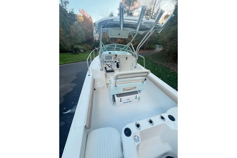 Slide: The Image of 2005 Sailfish 218 WAC boat interior with seating and steering console, surrounded by trees. - 13