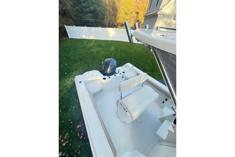 Slide: The Image of 2005 Sailfish 218 WAC boat with white seating, parked on grass near a fence. - 35