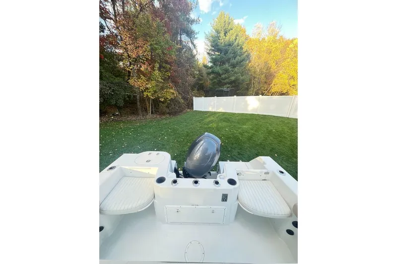 Slide: The Image of 2005 Sailfish 218 WAC boat with outboard motor, set in a grassy backyard. - 48