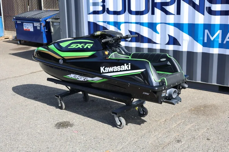 Slide: The Image of 2022 Kawasaki Jetski SX-R in black and green on a stand, outdoor setting. - 2