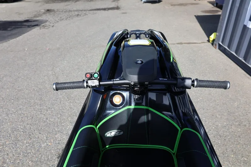 Slide: The Image of 2022 Kawasaki Jetski SX-R handlebars and seat, black with green accents, on pavement. - 9
