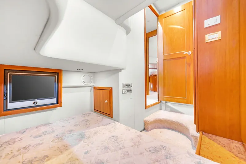 Slide: The Image of 2007 Silverton 45 Convertible yacht interior with TV, wooden cabinetry, and cozy bedding. - 14