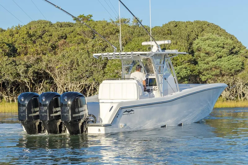 Slide: The Image of 2015 Invincible 39 Open Fisherman boat on calm water, surrounded by lush greenery. - 5