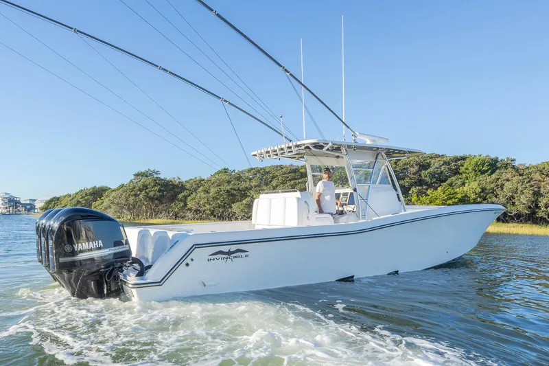 Slide: The Image of 2015 Invincible 39 Open Fisherman boat on calm water, surrounded by lush greenery. - 9