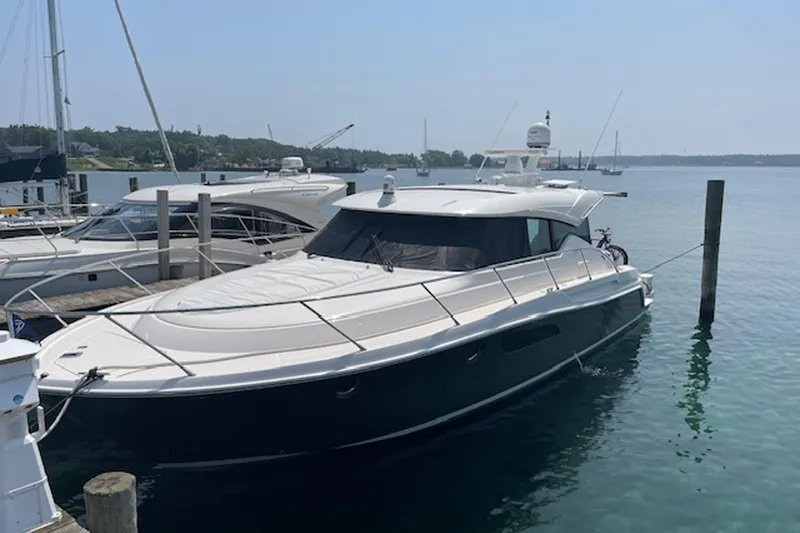 Slide: The Image of 2018 Tiara 44 Coupe yacht docked in a serene marina setting. - 2