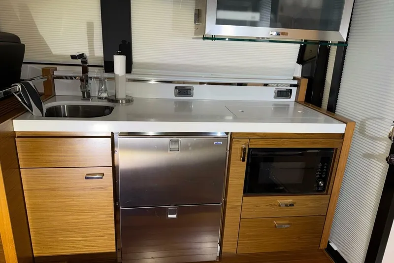 Slide: The Image of Modern kitchen area in a 2018 Tiara Yachts C44 Coupe, featuring sleek appliances and wood cabinetry. - 9