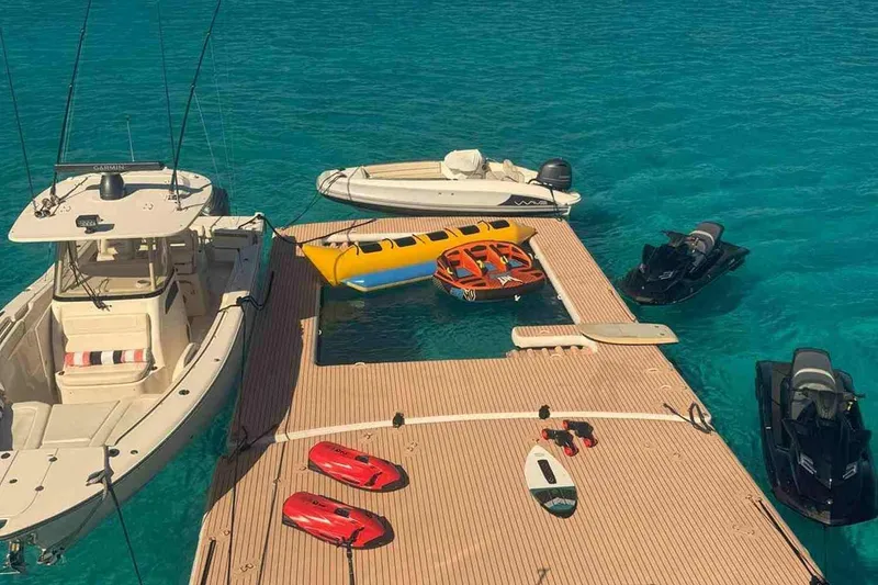 Slide: The Image of Floating dock with boats, jet skis, and water toys on clear blue water. - 29