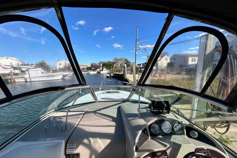 Slide: The Image of 2007 Sea Ray 260 Sundancer cockpit view, navigating a narrow waterway under clear blue skies. - 8