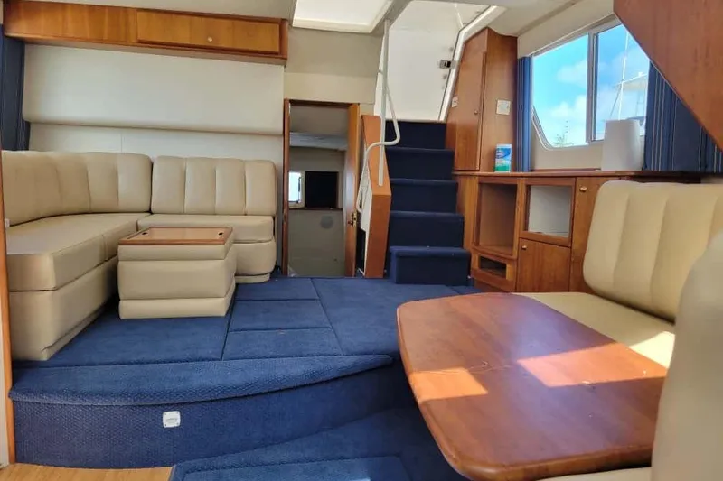 Slide: The Image of 1999 Silverton 392 Motor Yacht interior with beige seating and blue accents, docked by water. - 10