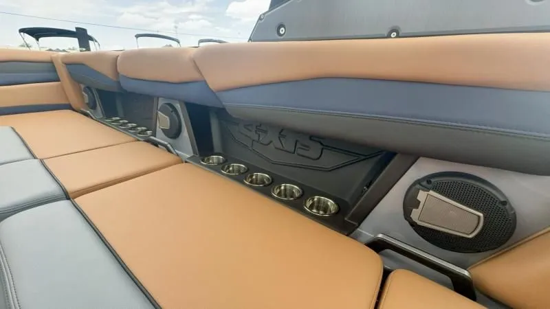 Slide: The Image of 2024 Axis A245 boat interior with tan and gray seating, cup holders, and speaker system. - 19