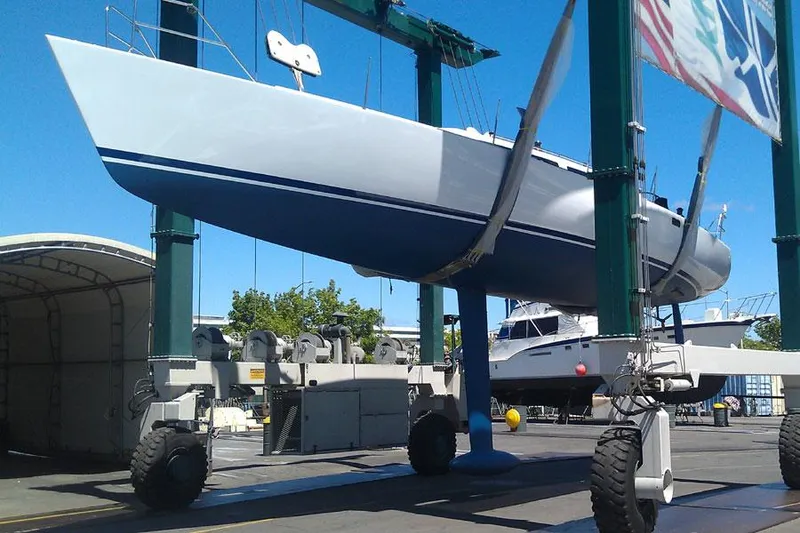 Slide: The Image of 1980 Santa Cruz SC 50 sailboat being lifted at a marina under clear blue skies. - 16