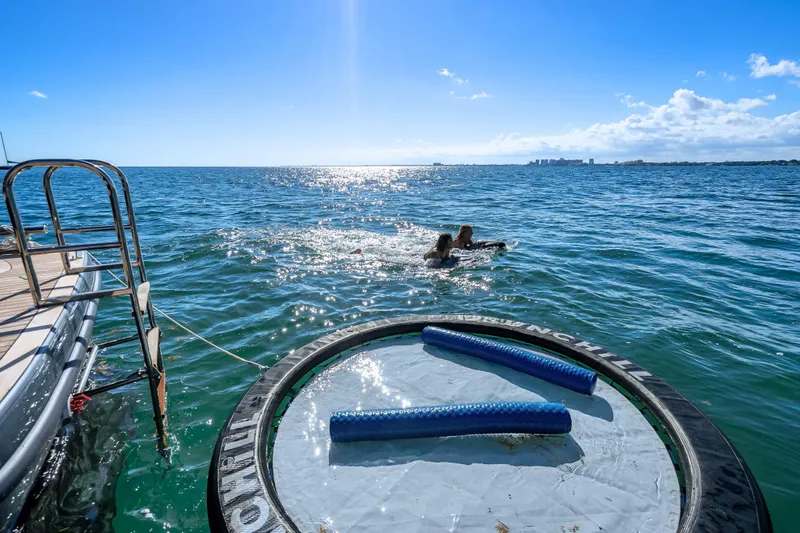 Slide: The Image of Sunreef 60 Power yacht with swimmers and floating mat on sunny ocean, 2026 model. - 18