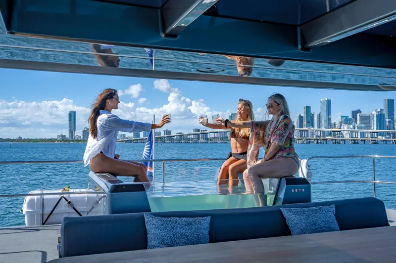 Slide: The Image of Women enjoying drinks on a 2026 Sunreef 60 Power yacht with city skyline backdrop. - 20