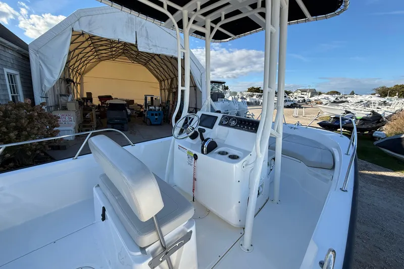 Slide: The Image of 2021 Boston Whaler 190 Montauk boat interior with console and seating, parked near a storage shed. - 13