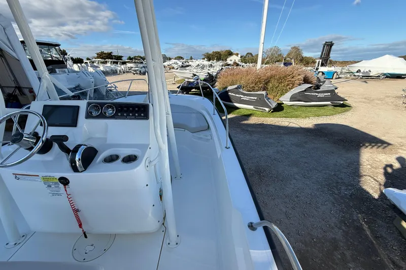 Slide: The Image of 2021 Boston Whaler 190 Montauk boat interior with steering console, parked near jet skis. - 17