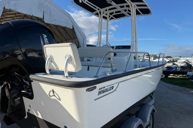 Slide: The Image of 2021 Boston Whaler 190 Montauk boat with Mercury engine, parked outdoors under blue sky. - 6