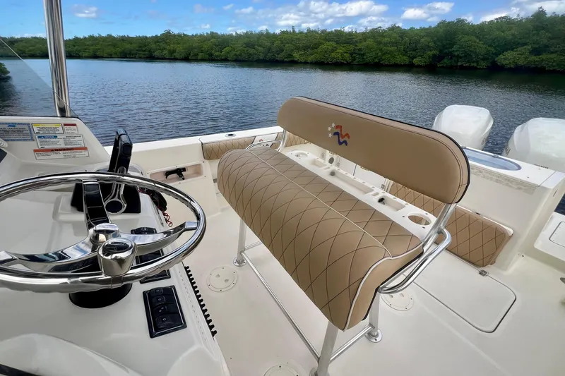 Slide: The Image of 2005 Pursuit 2670 Center Console boat interior with steering wheel and seating, near a scenic waterway. - 10