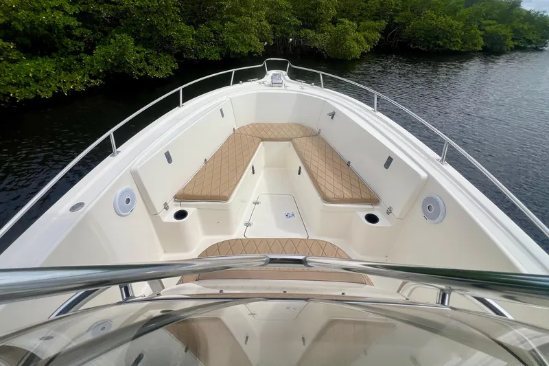 Slide: The Image of 2005 Pursuit 2670 Center Console boat with cushioned seating, docked near lush greenery. - 15