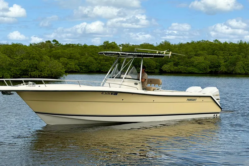 Slide: The Image of 2005 Pursuit 2670 Center Console boat on calm water with lush green background. - 2