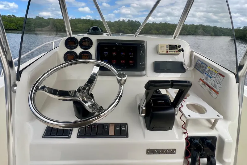 Slide: The Image of 2005 Pursuit 2670 Center Console boat dashboard with steering wheel and controls. - 5