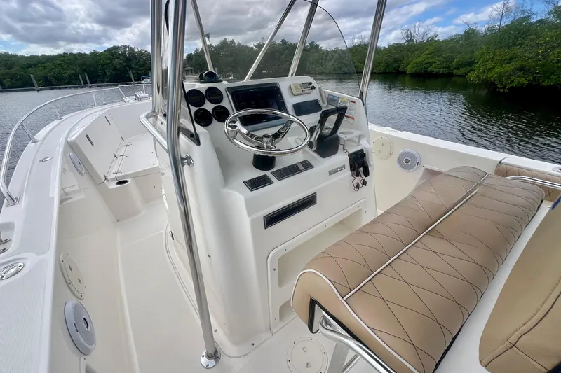 Slide: The Image of 2005 Pursuit 2670 Center Console boat interior with steering wheel and seating, near water. - 9