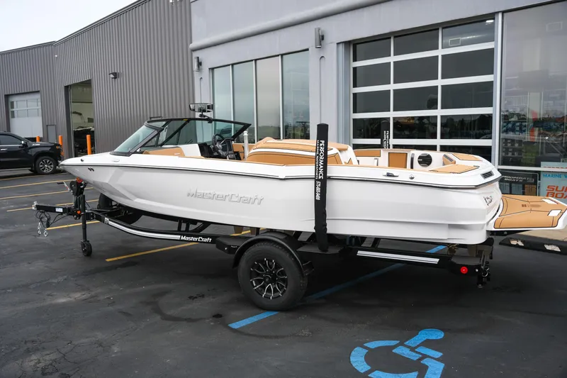 Slide: The Image of 2026 MasterCraft ProStar 190 boat on trailer, parked outside a building. - 2