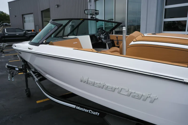 Slide: The Image of 2026 MasterCraft ProStar 190 boat with tan interior, parked outside a building. - 4