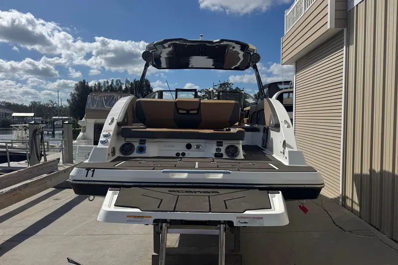 Slide: The Image of 2022 Scarab 285 ID boat docked, rear view with seating and speakers visible. - 13