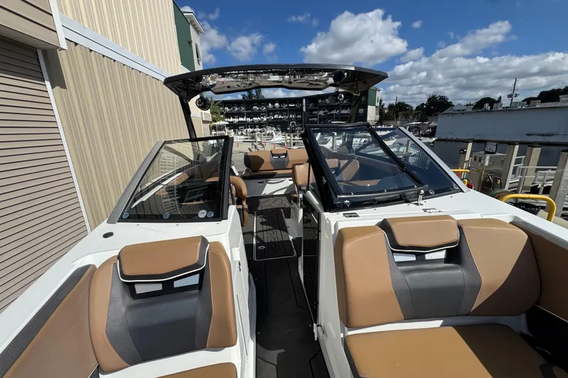 Slide: The Image of 2022 Scarab 285 ID boat interior with tan seating and glass windshields, docked under blue sky. - 41