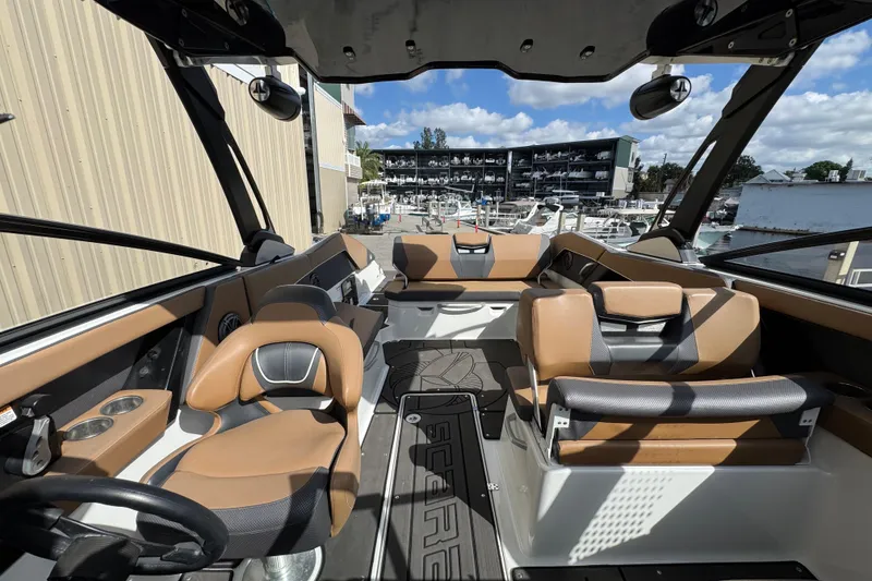 Slide: The Image of 2022 Scarab 285 ID boat interior with tan and black seating at a marina. - 42