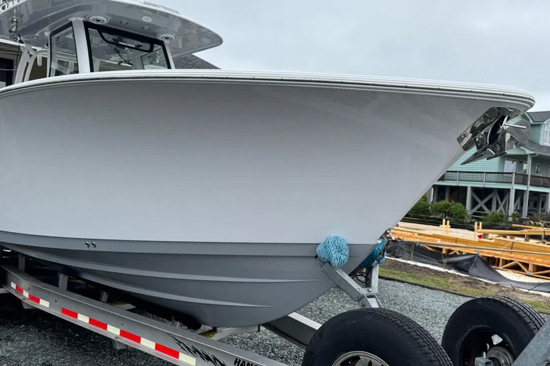 Slide: The Image of 2021 Sportsman Open 322 Center Console boat on trailer, parked near coastal homes. - 3