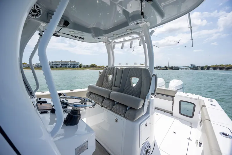 Slide: The Image of 2021 Sportsman Open 322 Center Console boat interior with helm and seating, on calm water. - 33