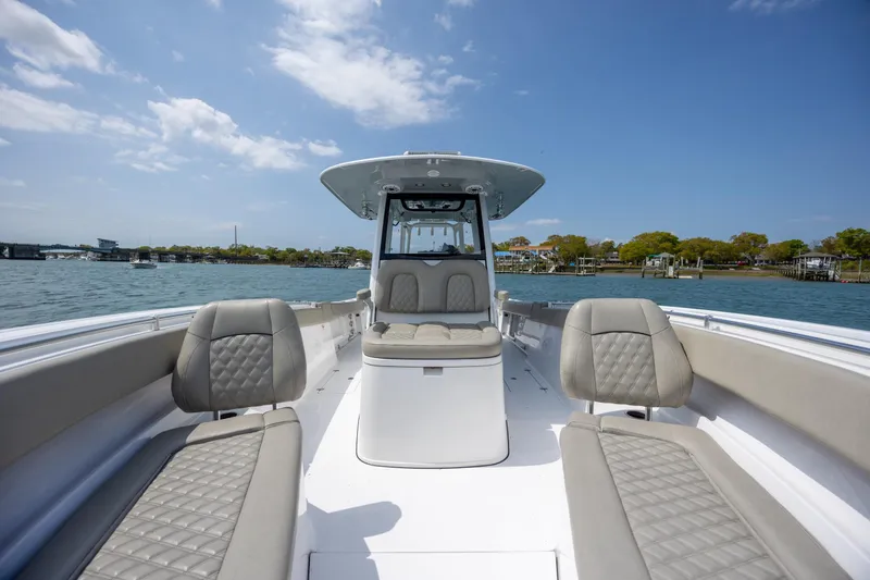 Slide: The Image of 2021 Sportsman Open 322 Center Console boat interior with cushioned seating on a sunny day. - 40