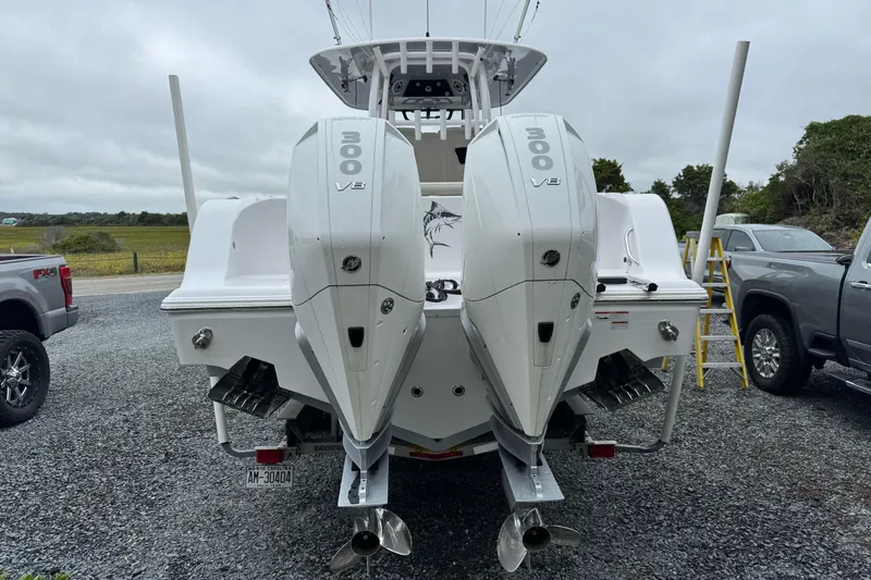 Slide: The Image of 2021 Sportsman Open 322 Center Console with twin 300 V8 engines, parked on gravel. - 7
