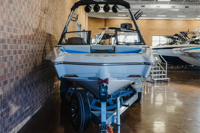 Slide: The Image of 2021 Axis A22 boat displayed indoors on a trailer, surrounded by other boats. - 3