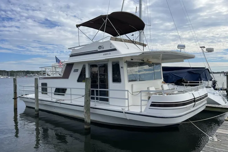 The Image of 1991 Gibson 37 Houseboat docked at marina under cloudy sky. - 0