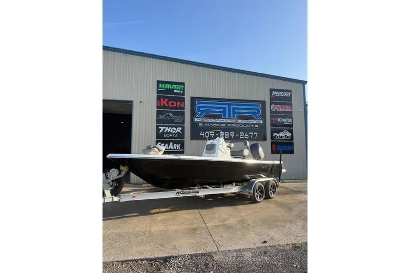 The Image of 2025 NauticStar 214 Bay boat on trailer outside marine products store. - 0