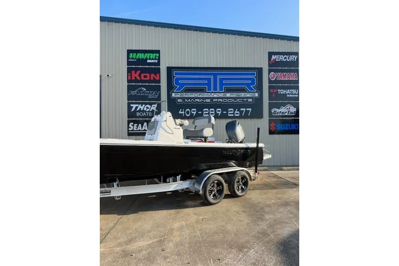 Slide: The Image of 2025 NauticStar 214 Bay boat on trailer outside marine products store. - 1