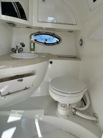 Slide: The Image of 1999 Cobalt 293 boat bathroom with sink, toilet, and porthole window. - 13