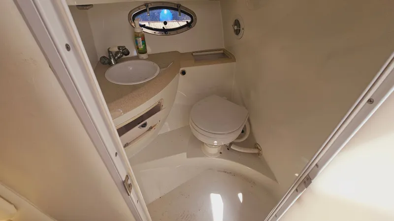 Slide: The Image of 1999 Cobalt 293 boat bathroom with sink, toilet, and porthole window. - 17