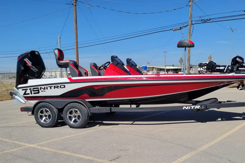 The Image of 2026 Nitro Z19 XL Pro boat on trailer, red and black design, parked outdoors. - 0