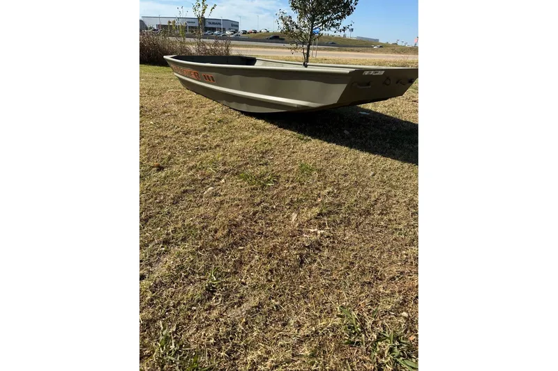 The Image of 2026 Tracker Grizzly 10 Jon boat on grass, sunny day, dealership in background. - 0