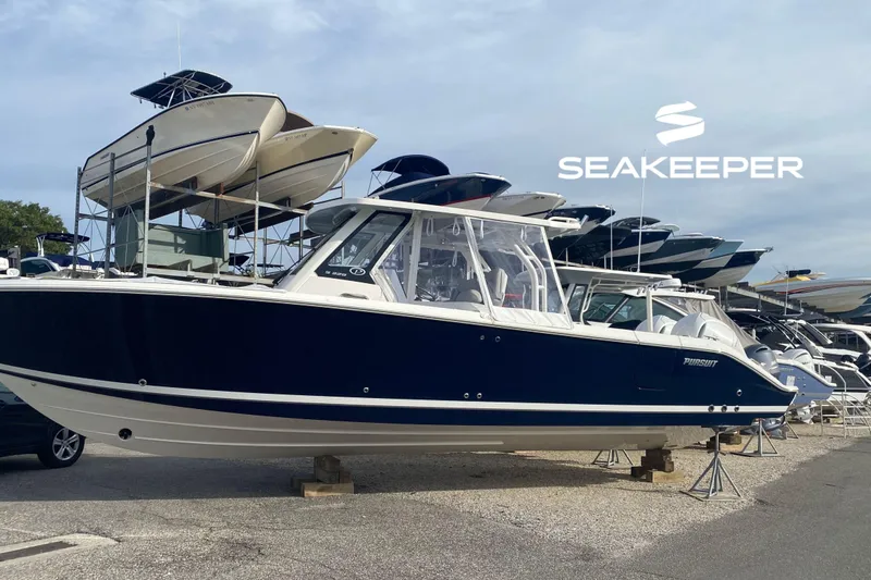 The Image of 2024 Pursuit S 328 Sport boat displayed at a marina with Seakeeper logo. - 0