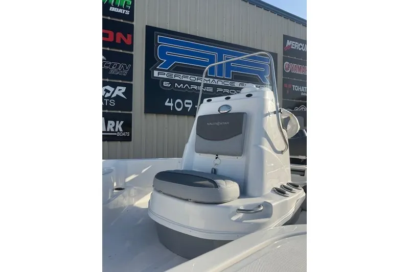 Slide: The Image of 2025 NauticStar 214 Bay boat at marine dealership, showcasing console and seating. - 2
