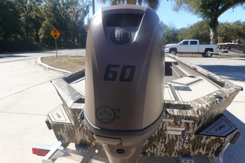 Slide: The Image of 2026 Avid 16 Commander boat with 60 HP engine, camo design, parked on trailer. - 18