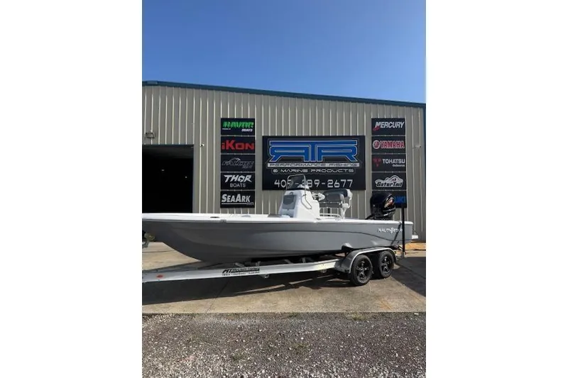 The Image of 2025 NauticStar 224 Bay boat on trailer outside marine shop. - 0
